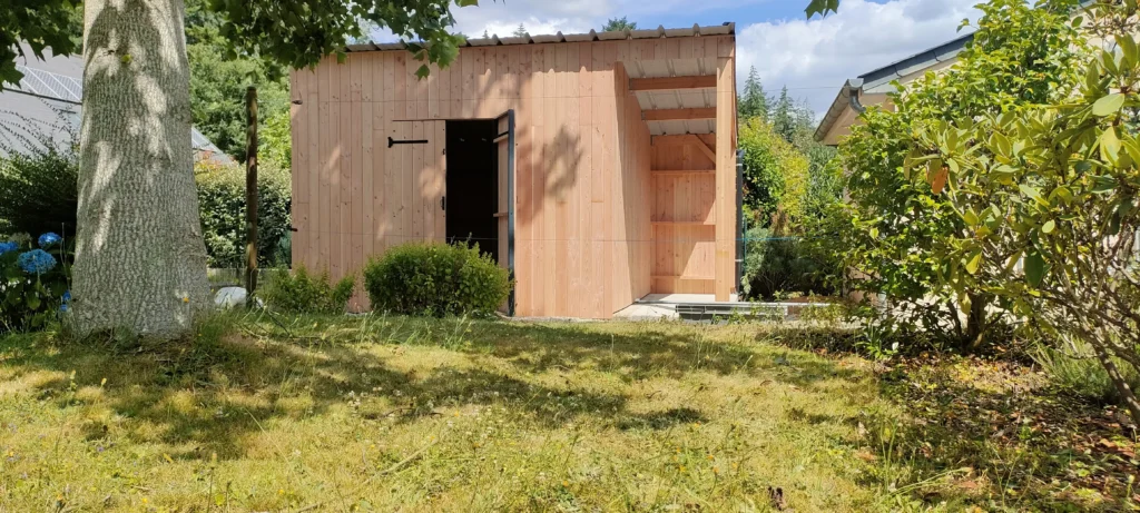 photo d'un abri de jardin au fond d'un jardin, sous un arbre
