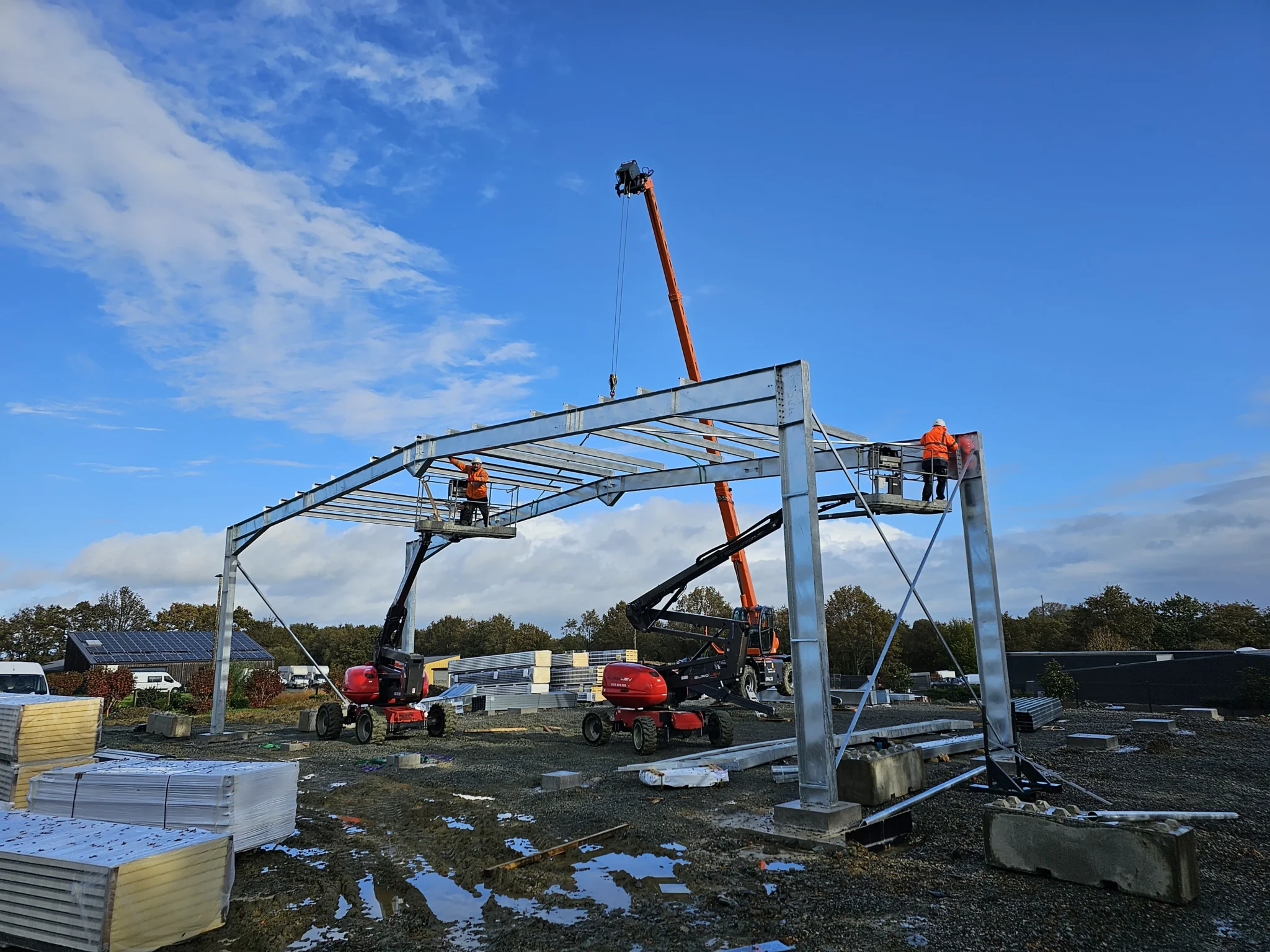 Nos réalisations : grand angle d'ouvriers et d'engins en train de monter une charpente métallique